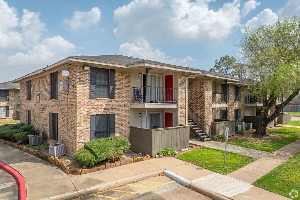 a brick apartment building with a red door and a sidewalk