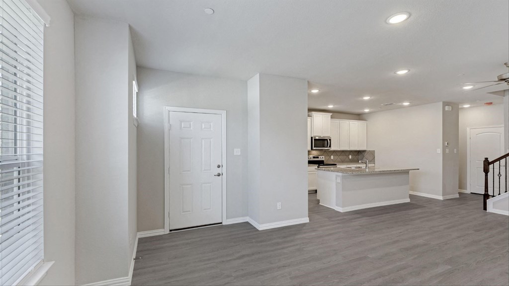 a renovated living room and kitchen with white walls and wood flooring