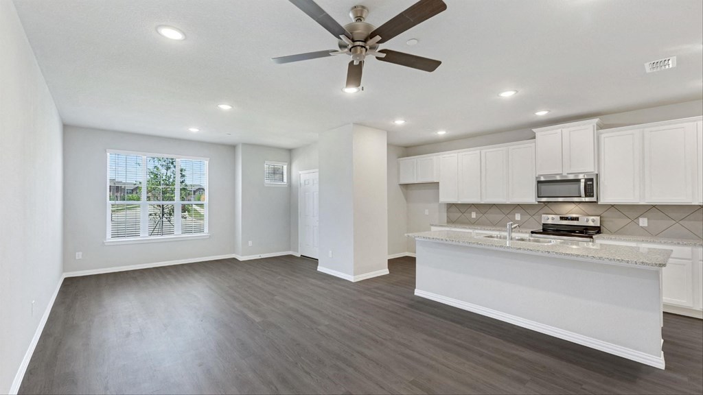an empty kitchen and living room with a ceiling fan