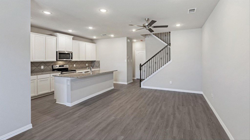 an open kitchen and living room with white cabinets and a ceiling fan