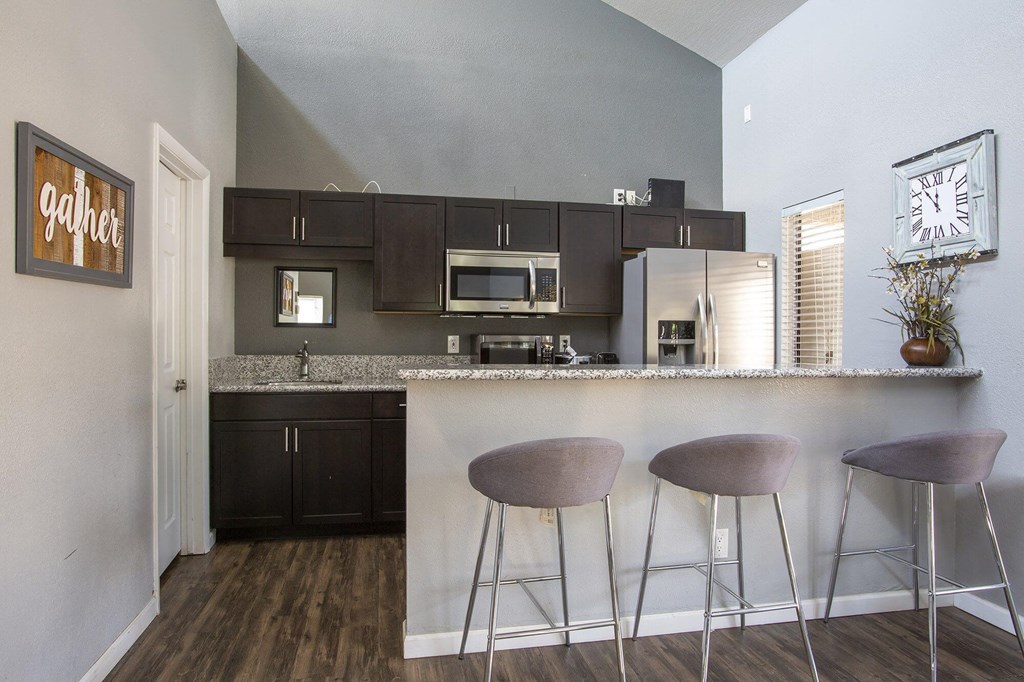 a kitchen with a bar with three stools