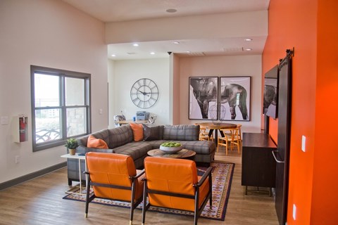 A living room with a grey couch and orange chairs.