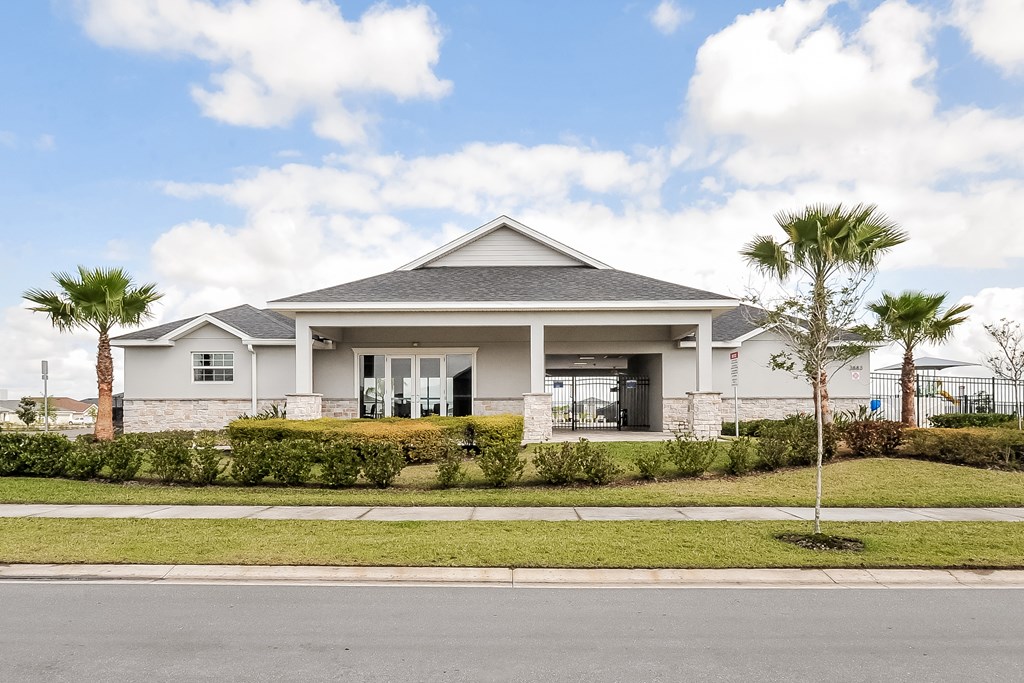A house with a grey roof and white walls is surrounded by greenery.