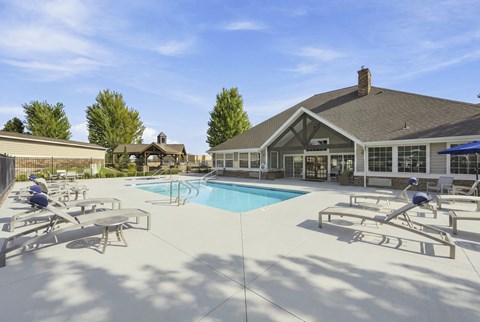 A pool area with sun loungers and a building in the background.