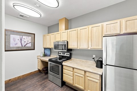 A kitchen with wooden cabinets and a stainless steel refrigerator.