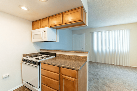 A kitchen with a white stove and wooden cabinets.