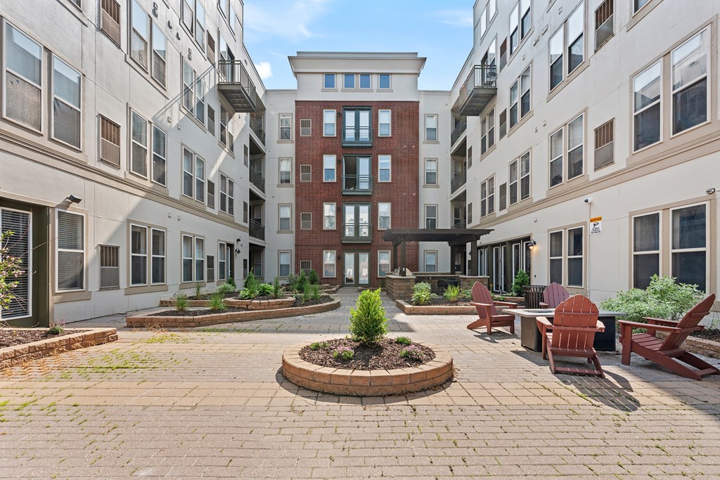 A courtyard with a brick circle in the middle and a red bench on the right.