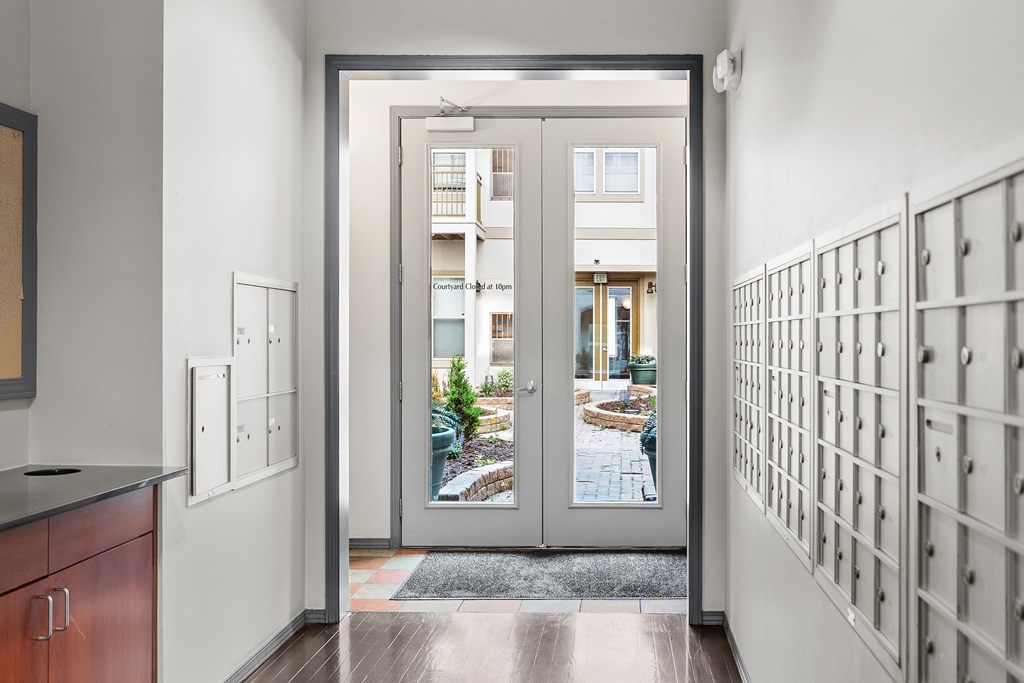 A modern interior with a view of a courtyard through a glass door.