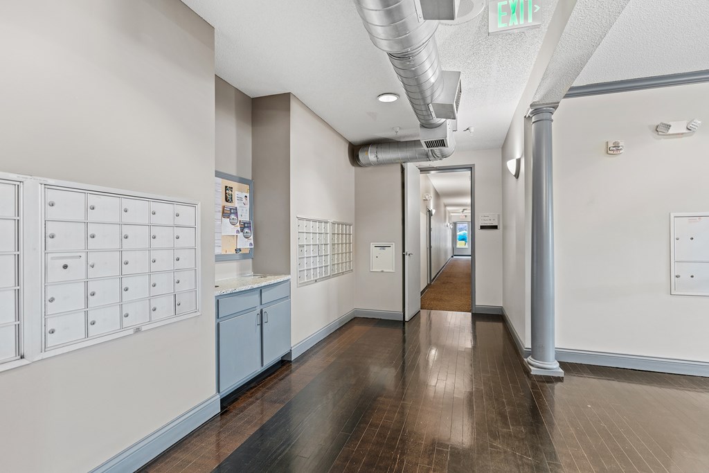 A long hallway with a white wall and a blue cabinet.