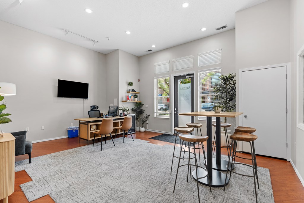 A modern living room with a grey rug and a television on the wall.