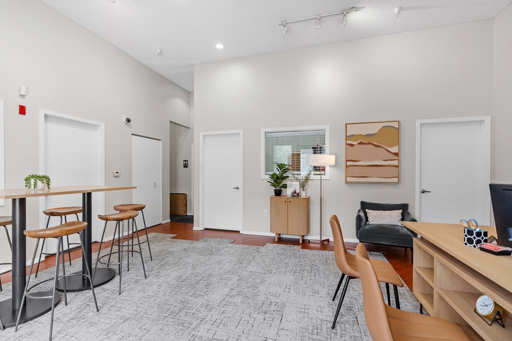 A room with a desk, chairs, and a potted plant.