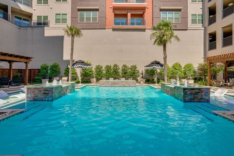 A swimming pool in front of a building with palm trees.