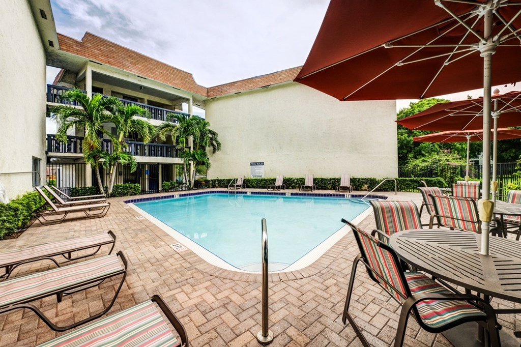 Sparkling pool with shaded seating at Coronado Springs Apartments in Palm Springs, FL. Pet-friendly community featuring resort-style amenities.