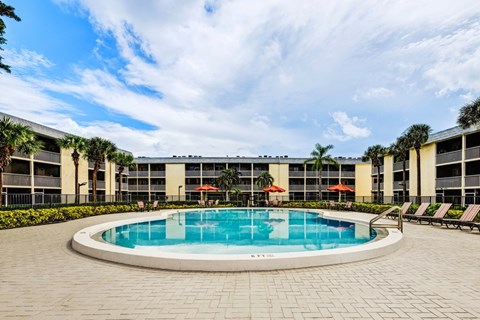 Resort-style swimming pool with lounge seating at Coronado Springs Apartments in Palm Springs, FL. Pet-friendly community offering one- and two-bedroom homes.