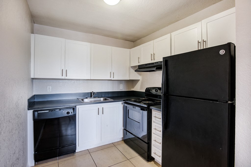an empty kitchen with black appliances and white cabinets