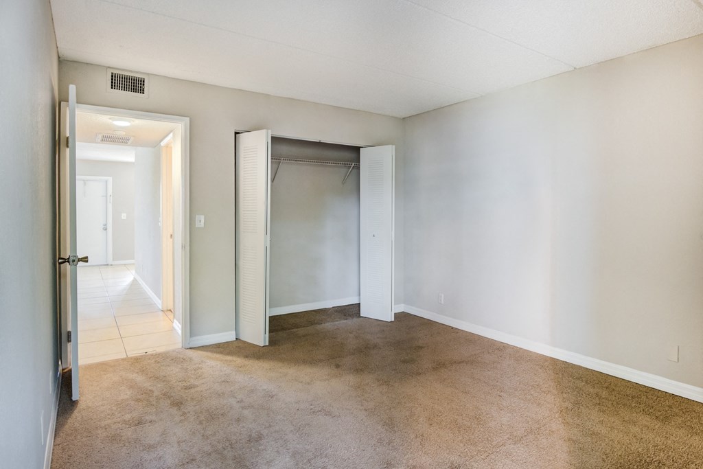 an empty living room with a closet and a tiled floor