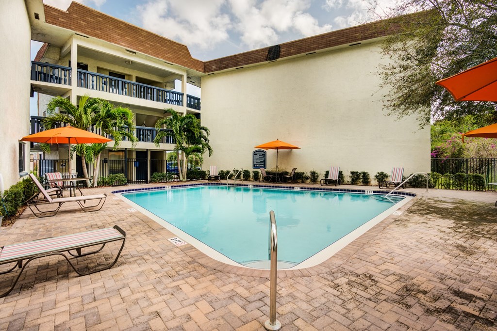 a swimming pool in front of a building with a resort style pool