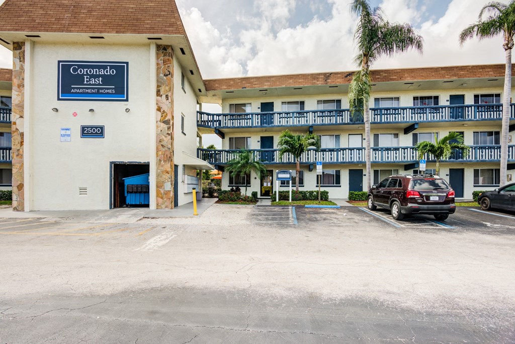 a large hotel building with a parking lot and a car parked in front of it