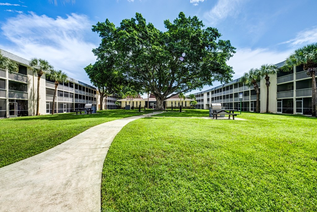 landscaped courtyard with green space and walking paths at Coronado Springs Apartments, a pet-friendly 1- and 2-bedroom community in Palm Springs, Florida.