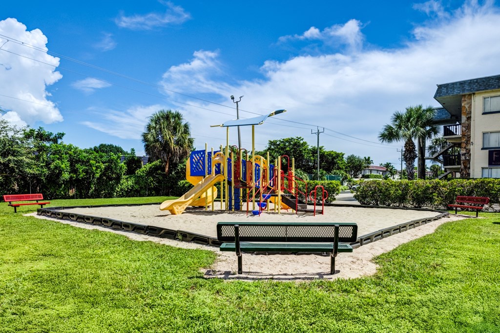 Outdoor playground surrounded by green lawns and palm trees at Coronado Springs Apartments in Palm Springs, FL, a pet-friendly community ideal for active lifestyles