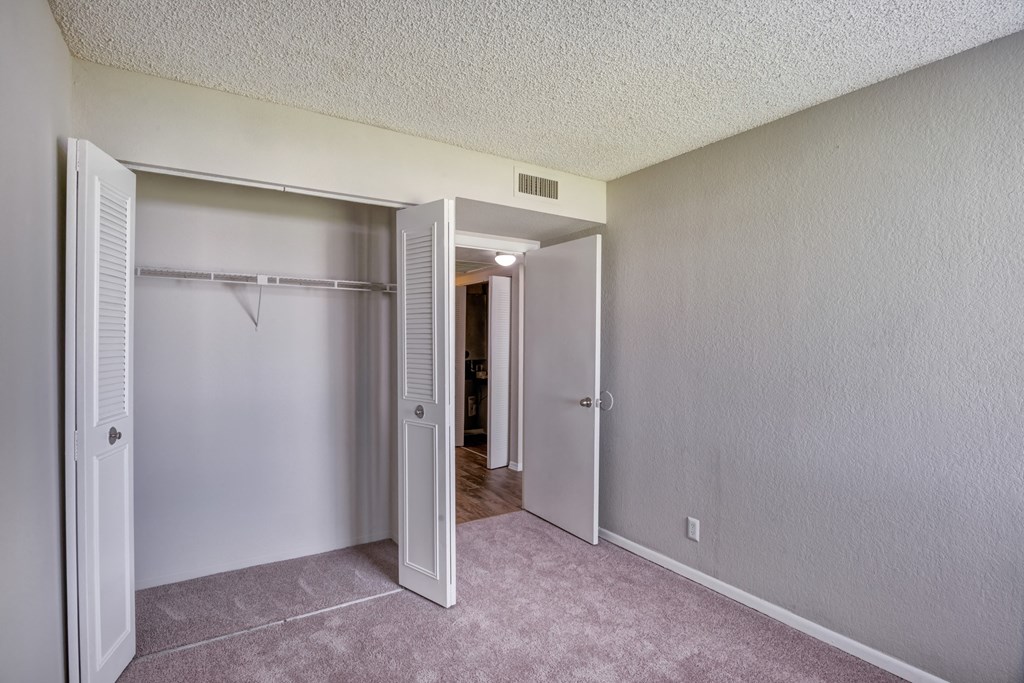 an empty bedroom with a closet and a door to a hallway
