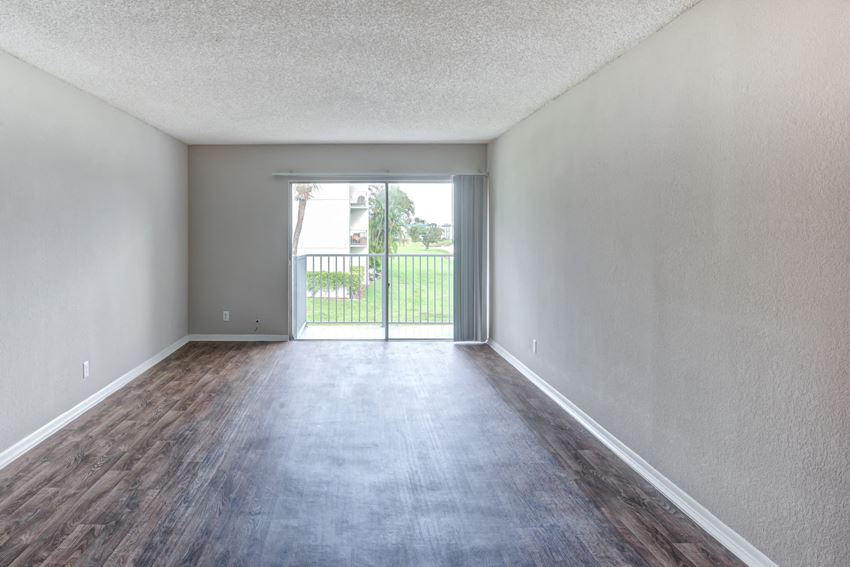 an empty living room with a sliding glass door to a balcony