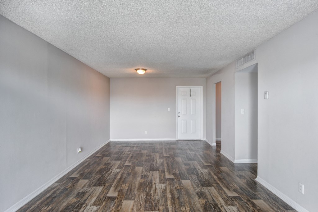 an empty living room with wood flooring and white walls