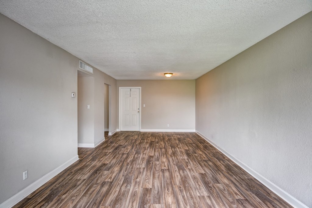 an empty living room with wood flooring and white walls