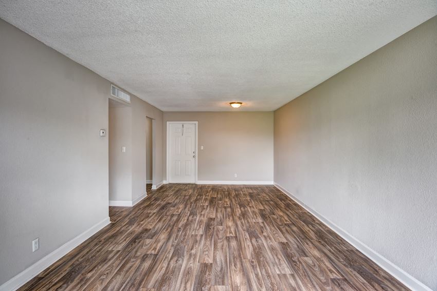 an empty living room with wood flooring and white walls