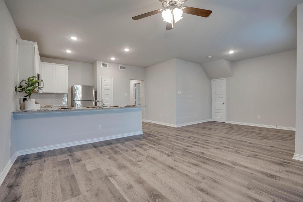 Houses In Forth Worth For Rent - Cottages at Summer Creek - Open-Concept Living Room with Wood-Style Floors, High Ceilings, Ceiling Fan, and Access to Kitchen