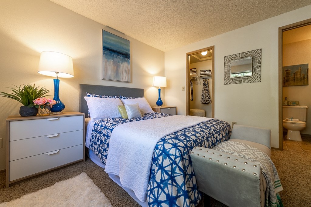 1 Bedroom Apartments In Kent, WA - Country Glen - A Cozy Bedroom With A Large Bed, Easy Access Walk-In Closet, Lamps, And A Bench At The Foot Of The Bed.