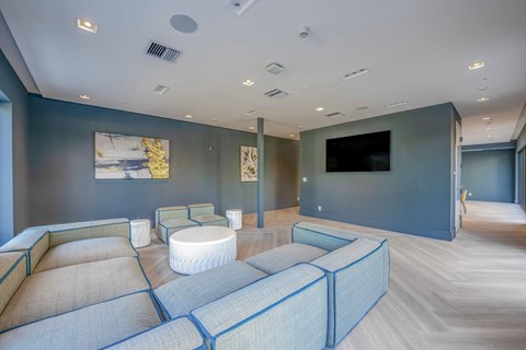 Modern apartment lounge area with sectional sofa, artwork, and herringbone wood floors.