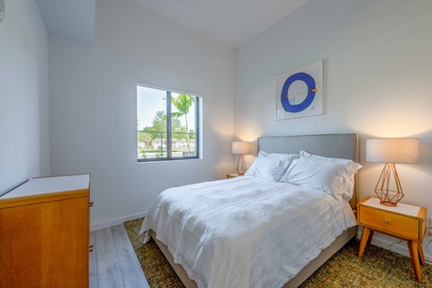 Bright bedroom with white walls, bed, and mid-century modern furniture.