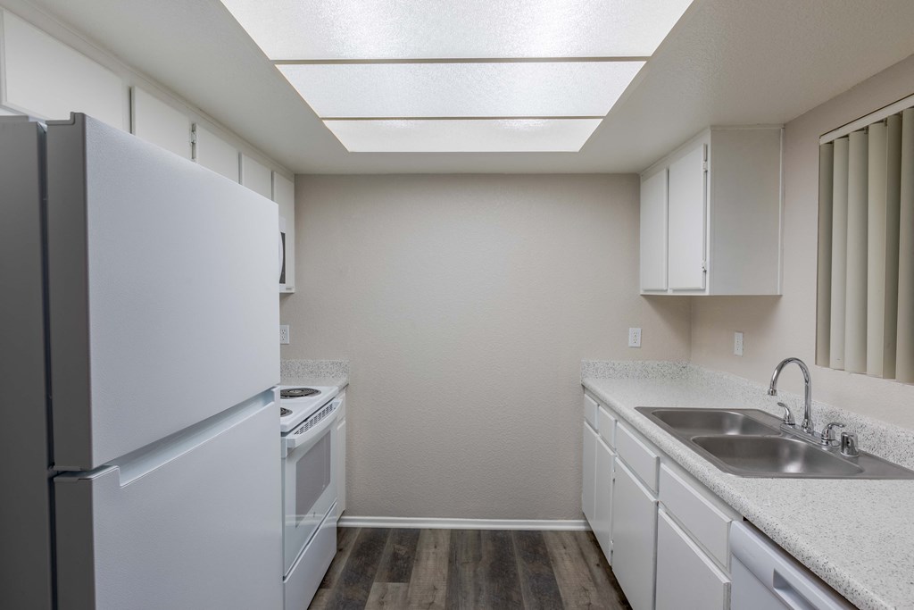 a kitchen with white cabinets and a sink and a refrigerator
