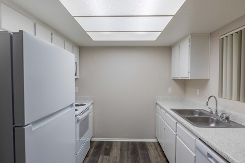 a kitchen with white cabinets and a sink and a refrigerator