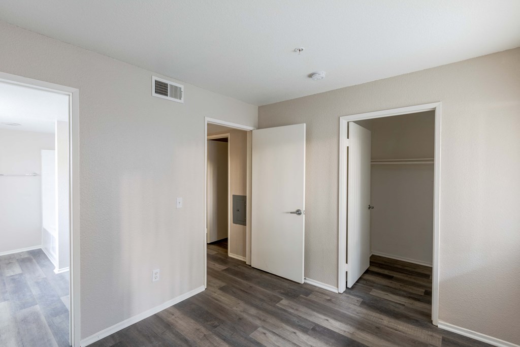the living room of an apartment with wood floors and white walls