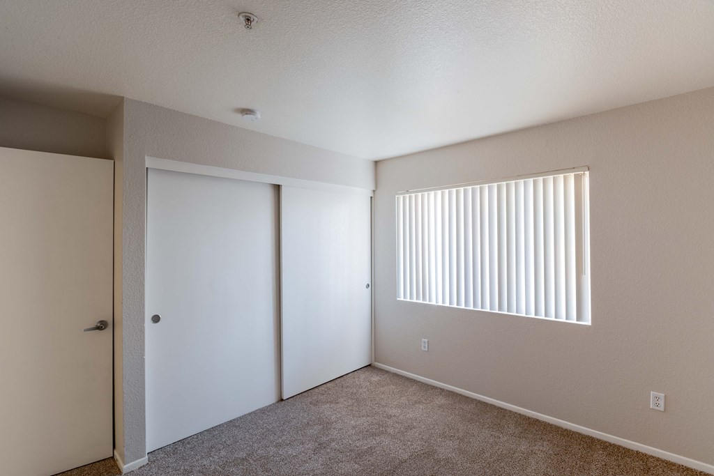 an empty bedroom with a closet and a window