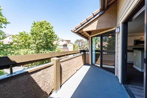 A balcony with a wooden railing and glass doors leading to a home interior.