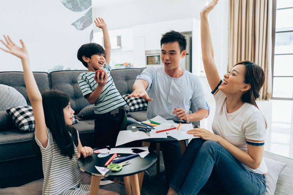 a group of people sitting around in a living room with their hands in the air