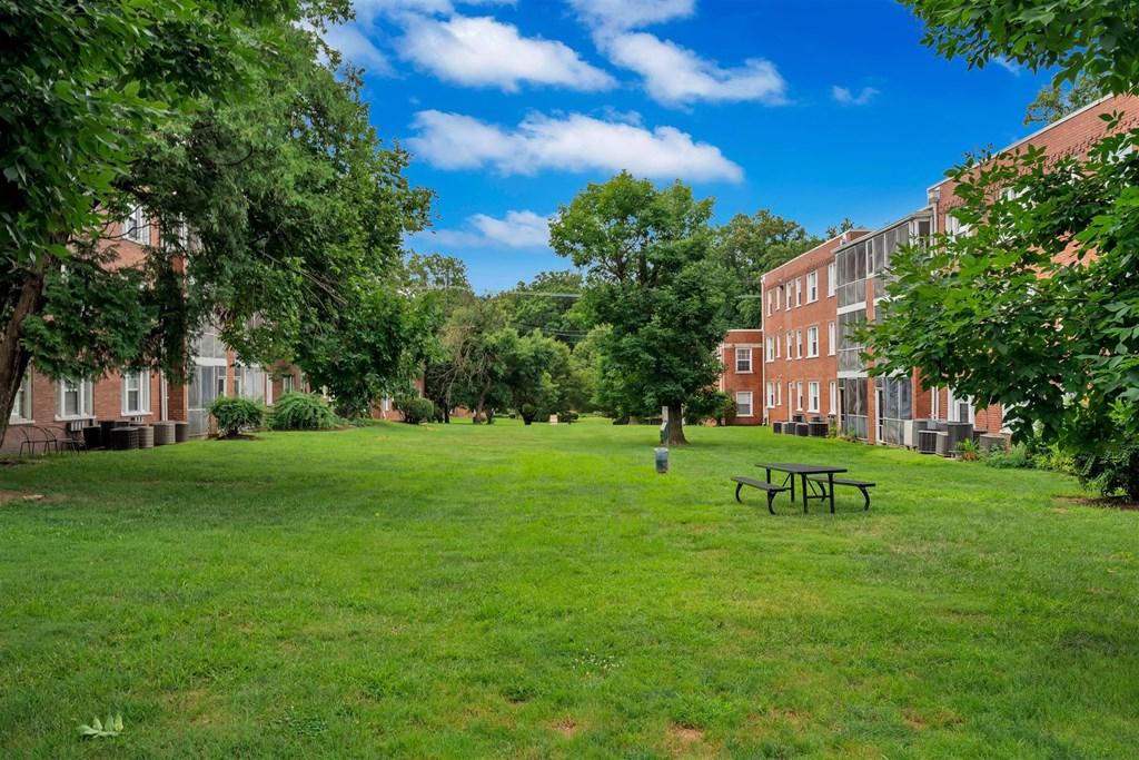 a green lawn with a picnic table in front of a brick building