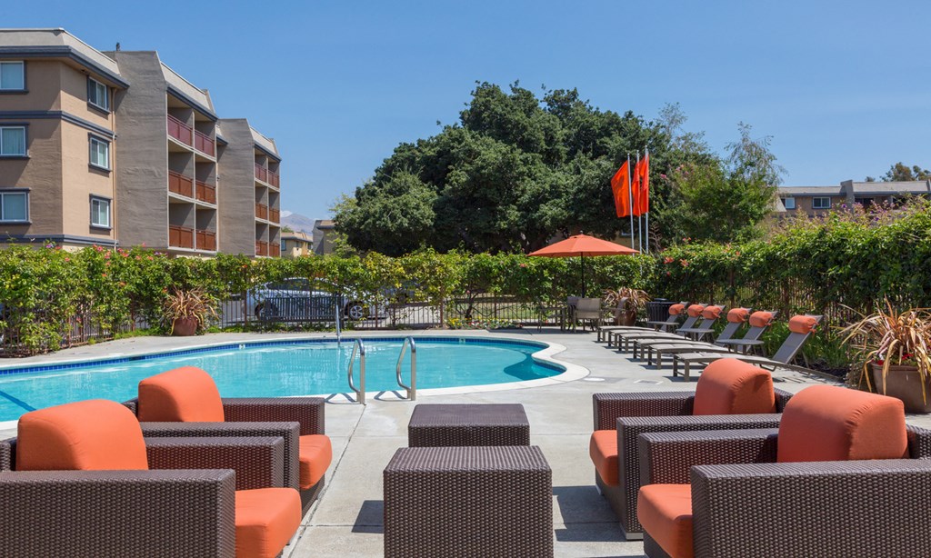 a swimming pool with chairs and umbrellas in front of a hotel