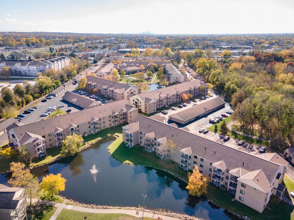 an aerial view of an apartment complex with a body of water and trees