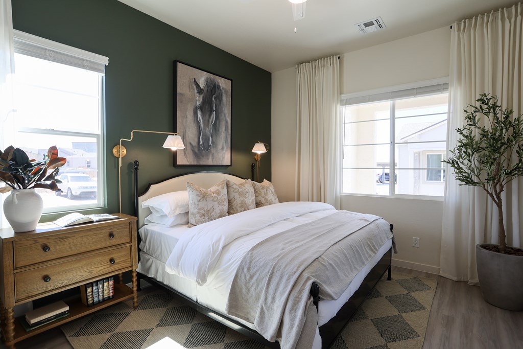 A bedroom with a large bed, a wooden dresser, and a painting on the wall.