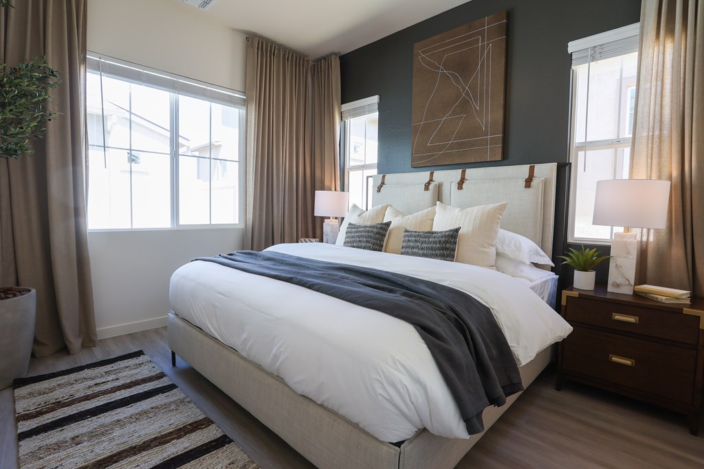 A bedroom with a large bed and a plant on the side table.