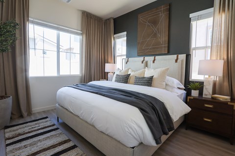 A bedroom with a large bed and a plant on the side table.