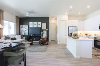 A modern living room with a grey sofa and a white kitchen.