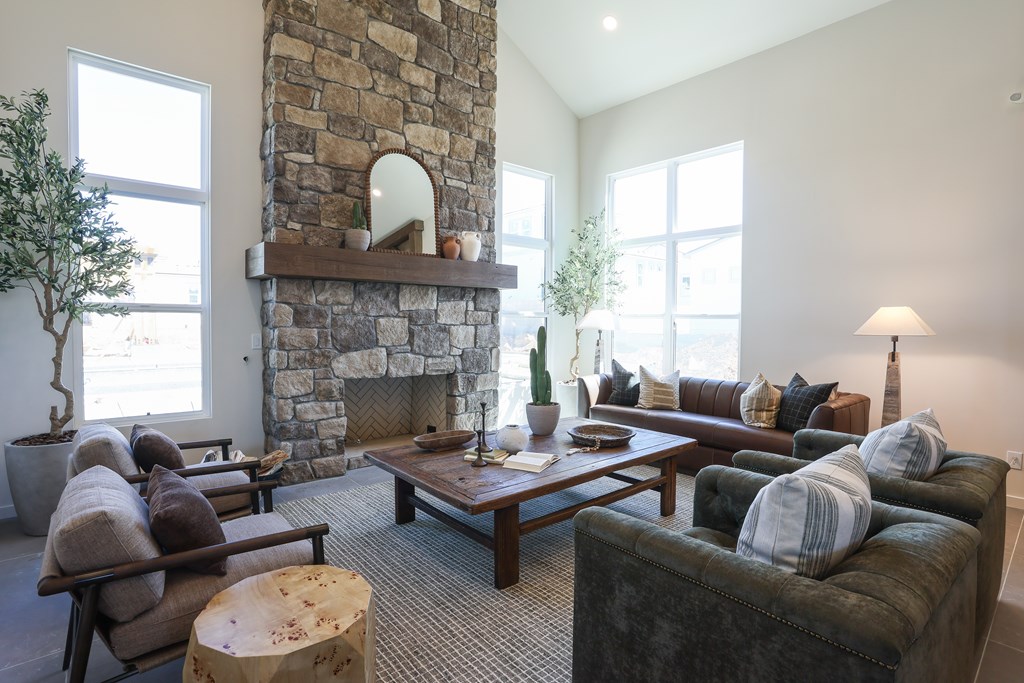 A living room with a stone fireplace and a variety of seating options.