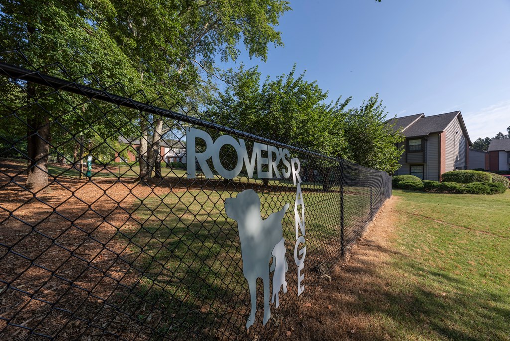 a sign on a fence in front of a dog park