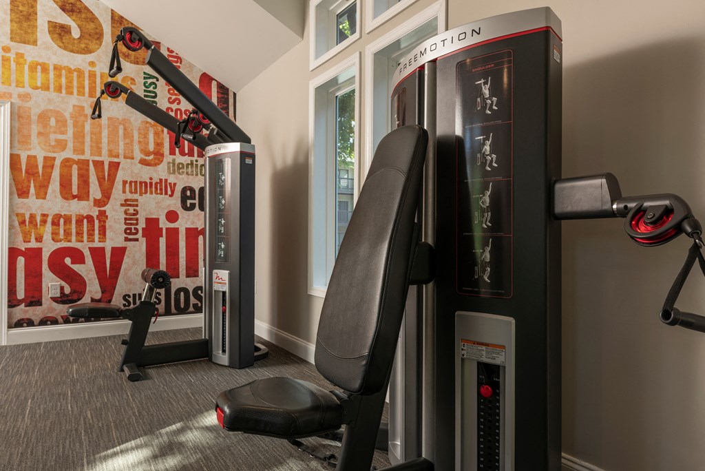 a gym with two machines and a chair in the corner
