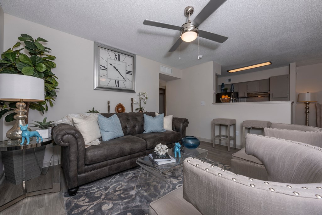 a living room with couches and chairs and a ceiling fan